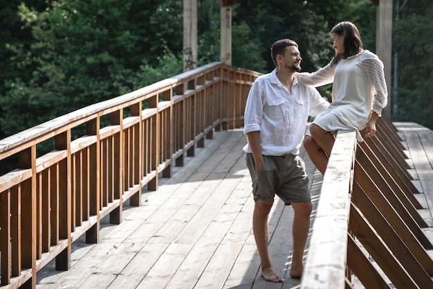 Una bella giovane coppia comunica su un ponte nella foresta, un appuntamento nella natura, una storia d'amore.