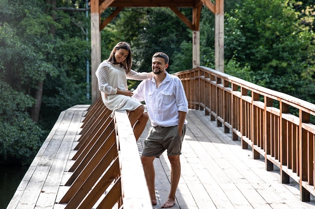 Una bella giovane coppia comunica su un ponte nella foresta, un appuntamento nella natura, una storia d'amore.