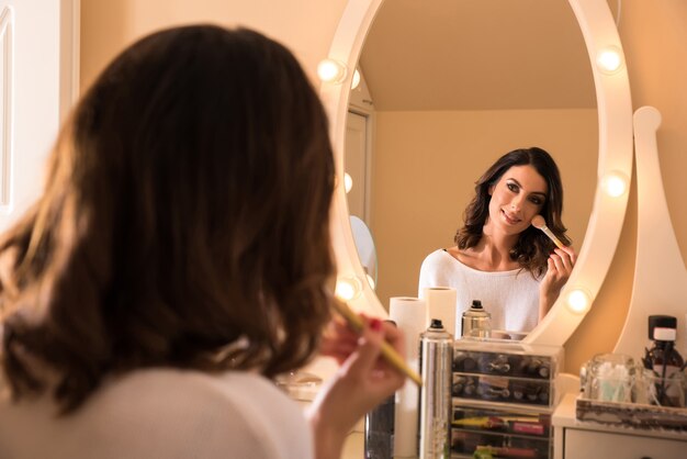 Una bella giovane donna a un tavolo da trucco