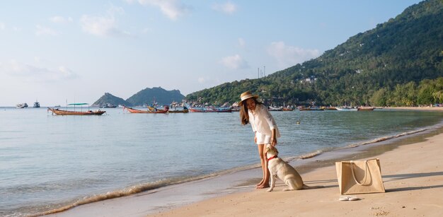 Una bella giovane donna asiatica che gioca con un cane sulla spiaggia