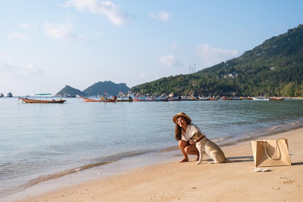 Una bella giovane donna asiatica che gioca con un cane sulla spiaggia