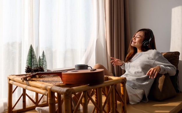 Una bella giovane donna asiatica si diverte ad ascoltare musica con le cuffie a casa concetti di felicità e relax