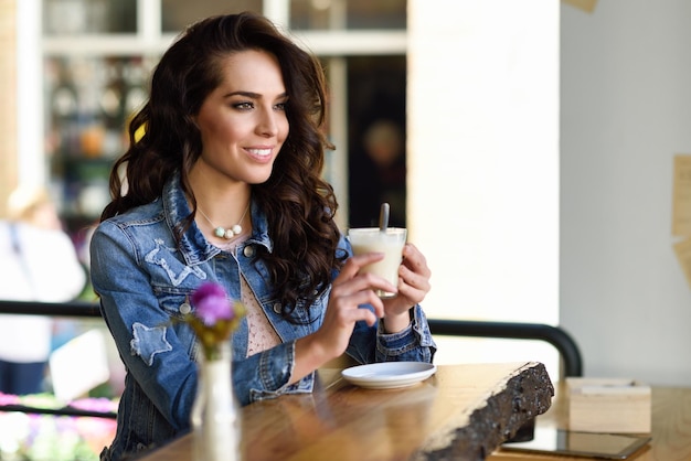 Una bella giovane donna che beve caffè in un bar.