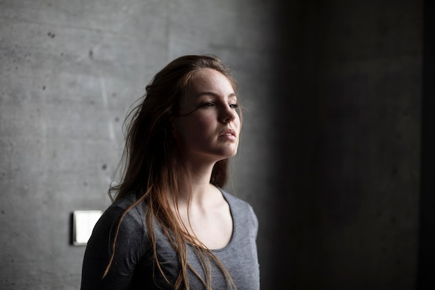 Una bella giovane donna che guarda lontano mentre si trova contro il muro.