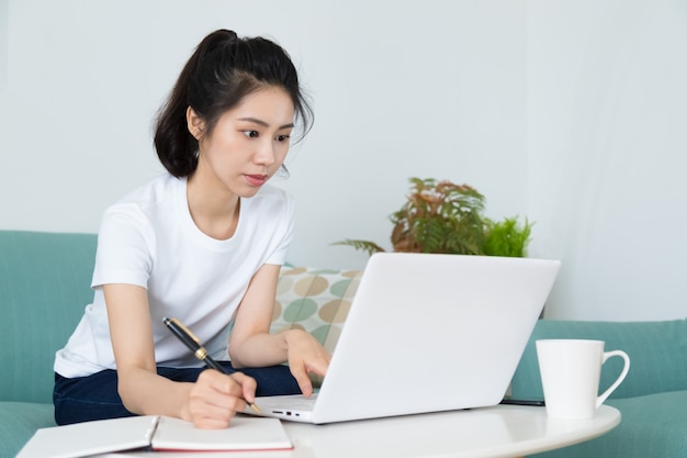 Una bella giovane donna che studia seduti al tavolo con il laptop a casa