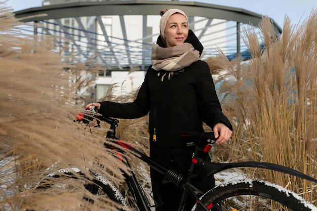 Una bella giovane donna che va in bicicletta in inverno