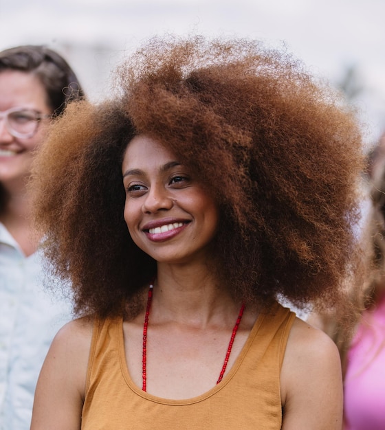 Una bella giovane donna con i capelli neri sorride nella folla.