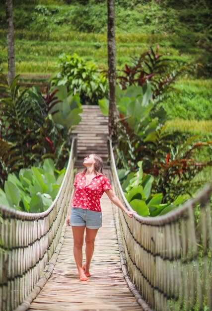 Una bella giovane donna è seduta su un ponte sospeso nella foresta tropicale