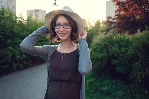 Una bella giovane donna incinta gode di una passeggiata serale attraverso un bellissimo parco verde.