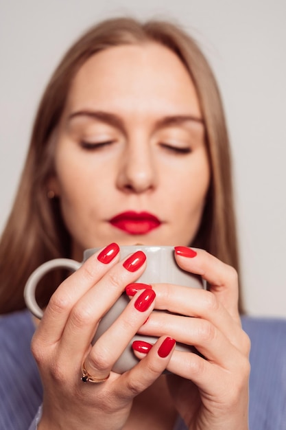 Una bella giovane donna seria sfocata in un vestito azzurro che esamina una tazza di caffè