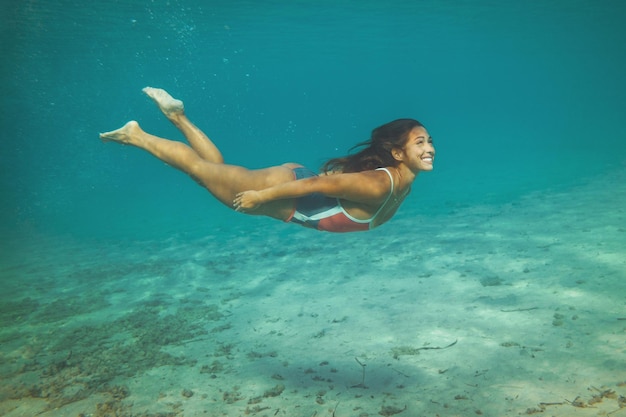 Una bella giovane donna si diverte durante le vacanze estive esplorando il fondale marino durante le immersioni subacquee in mare.