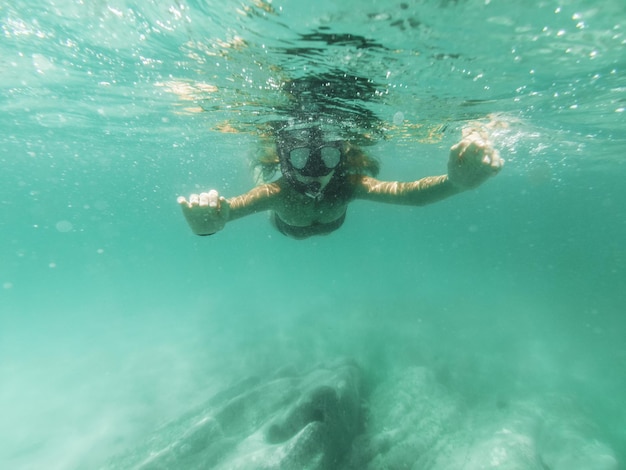 Una bella giovane donna si diverte durante le vacanze estive esplorando il fondale marino durante le immersioni subacquee in mare.