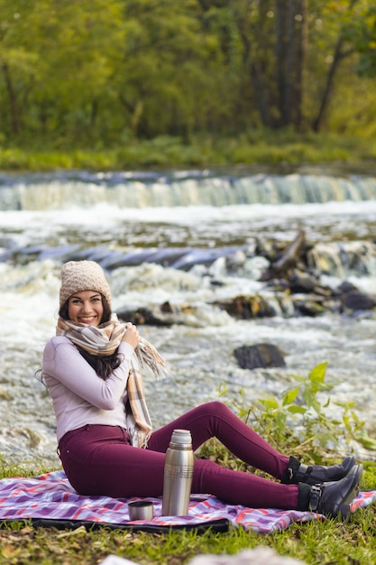 Una bella giovane donna sta riposando sulle rive di un fiume autunnale