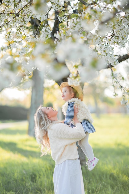 Una bella giovane madre con la sua piccola figlia sta riposando su un picnic nel giardino fiorito