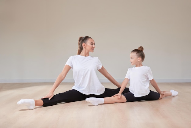 Una bella insegnante e una bambina stanno sedute in una classe di ginnastica Il concetto di educazione sport Pilates stretching stile di vita sano Media misto