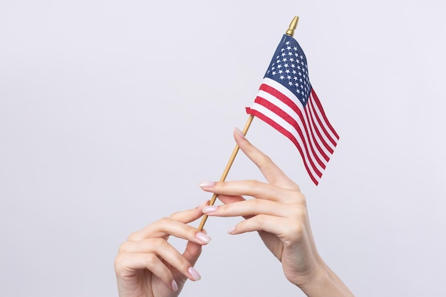 Una bella mano femminile tiene una bandiera americana su sfondo bianco