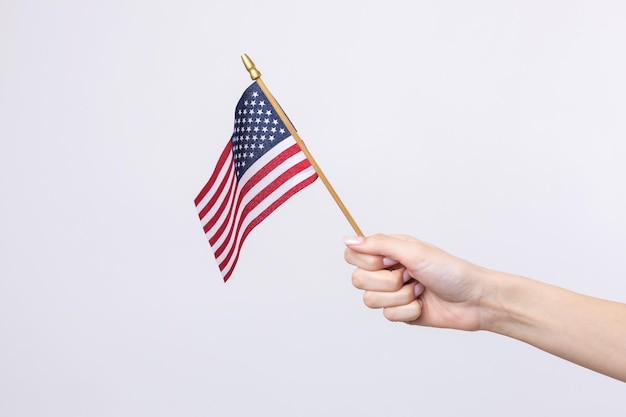 Una bella mano femminile tiene una bandiera americana su sfondo bianco
