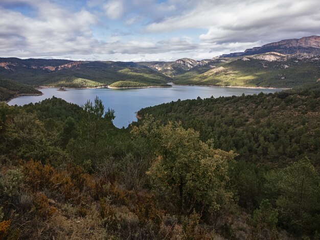 Una bella panoramica di un piccolo lago circondato da alberi e vieni nuvole in Catalunya, Spagna