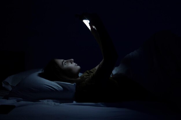 una bella ragazza a letto con un letto bianco e un telefono