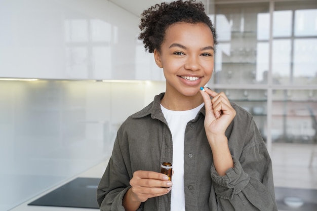 Una bella ragazza afroamericana sta assumendo la capsula Pillole contraccettive che assumono il concetto di assistenza sanitaria