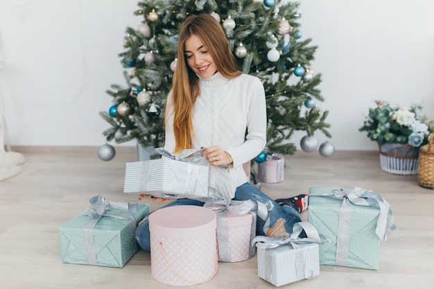 Una bella ragazza apre i regali di Natale.