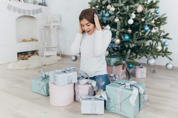 Una bella ragazza apre i regali di Natale.