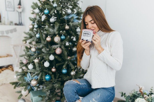 Una bella ragazza beve una tazza di caffè.