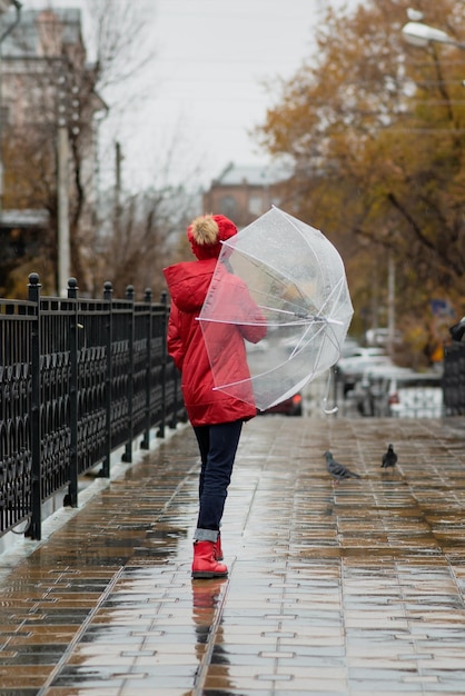 Una bella ragazza cammina sul ponte sotto la pioggia con un ombrello trasparente Autumn Weather