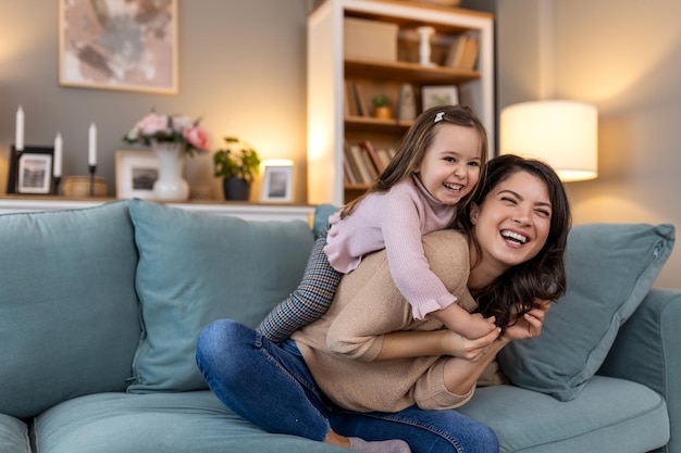 Una bella ragazza carina abbraccia sua madre sorridente mentre lei sta tenendo il suo amore famiglia felice e donna con bambino ragazza sorriso cura o lounge sul divano del soggiorno di casa