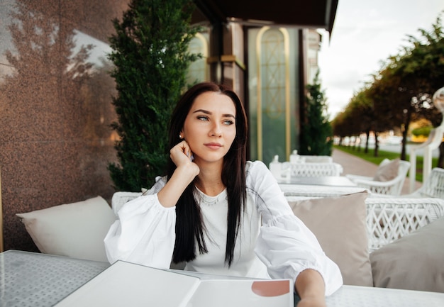 Una bella ragazza carina in un bar beve il caffè a un tavolo.