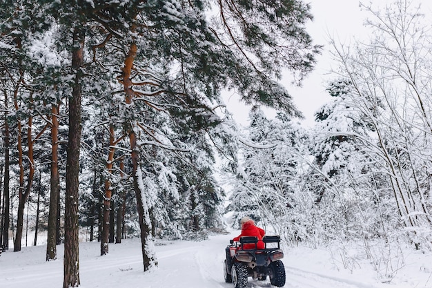 Una bella ragazza che cavalca un quadrociclo in una pittoresca zona nevosa