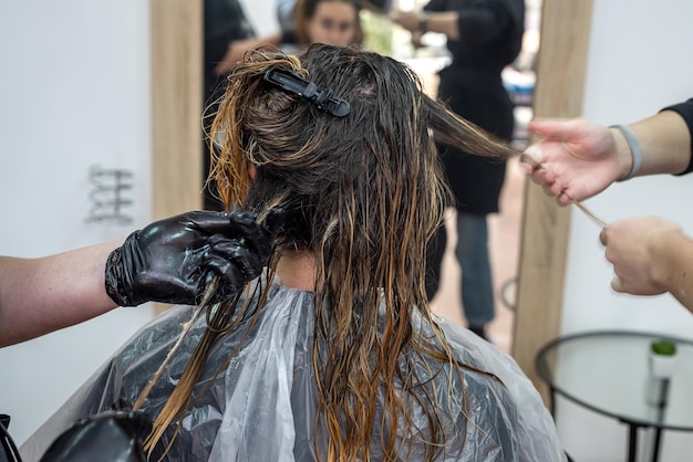 Una bella ragazza che è venuta per la prima volta al salone di bellezza si è sbiancata e si è asciugata i capelli per applicare la vernice Concetto di asciugatura dei capelli Concetto di salone di bellezza