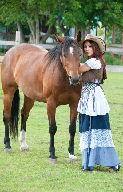 Una bella ragazza con un cappello da cowboy e un cavallo