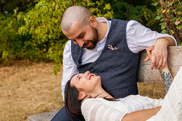 una bella ragazza con un vestito bianco e un tizio sono seduti su una panchina da vicino