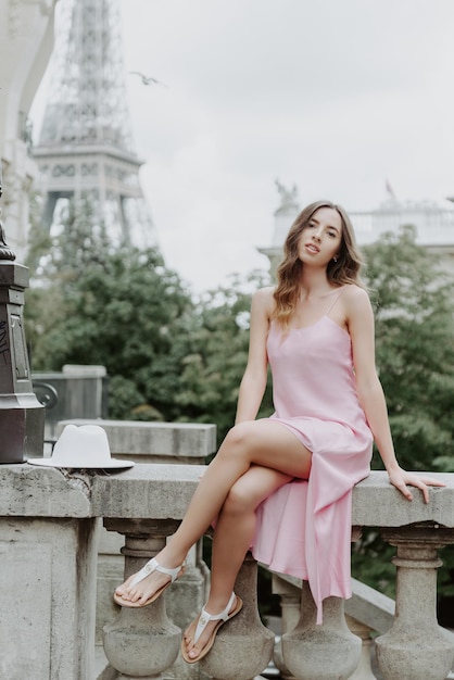 Una bella ragazza con un vestito rosa sullo sfondo della Torre Eiffel a Parigi Viaggio a Parigi