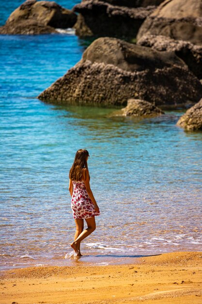 una bella ragazza dai capelli lunghi in un vestito si rilassa su una spiaggia paradisiaca sull'isola magnetica, in australia