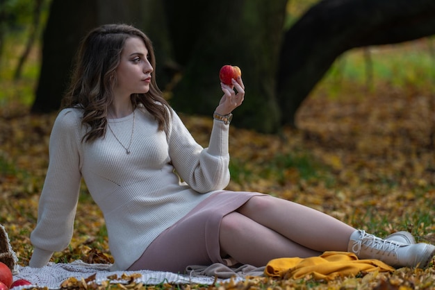 Una bella ragazza dai capelli scuri tiene in mano una mela e guarda il frutto