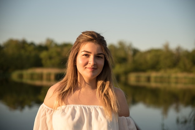 Una bella ragazza è in piedi sul molo sullo sfondo c'è un fiume un lago