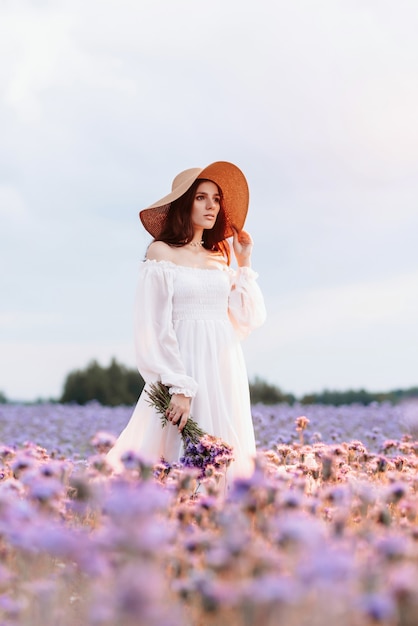 Una bella ragazza in abito bianco in un campo fiorito della Provenza in un'atmosfera romantica