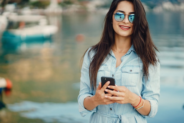 Una bella ragazza in un abito blu in piedi vicino all&#39;acqua