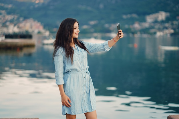 Una bella ragazza in un abito blu in piedi vicino all&#39;acqua