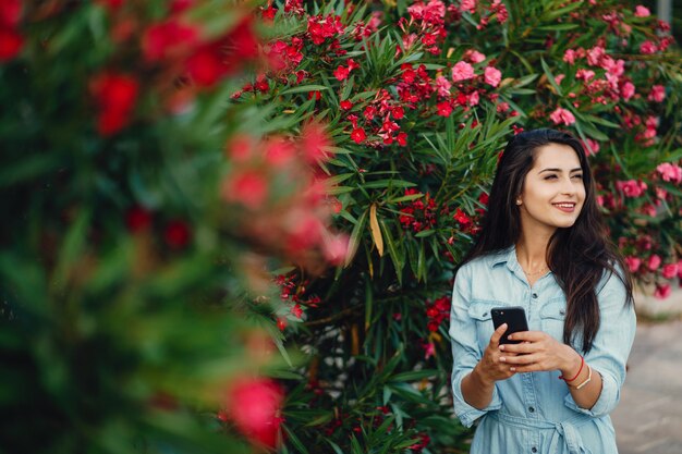 Una bella ragazza in un abito blu in piedi vicino all&#39;albero del fiore