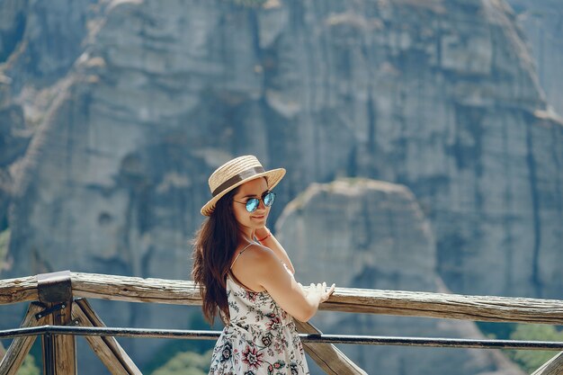 Una bella ragazza in un cappello di paglia in piedi e guardando le montagne