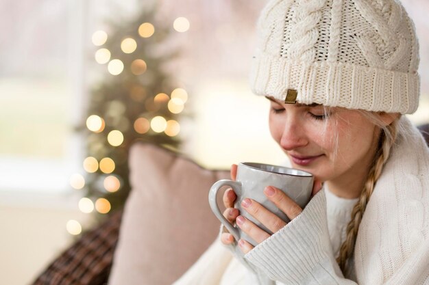 Una bella ragazza in una luminosa stanza di Natale legge un libro e beve il tè