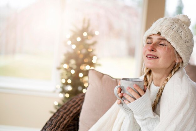 Una bella ragazza in una luminosa stanza di Natale legge un libro e beve il tè