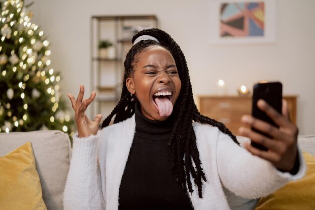 Una bella ragazza pazza di bellezza africana con i dreadlocks e un sorriso meraviglioso si rilassa sul divano