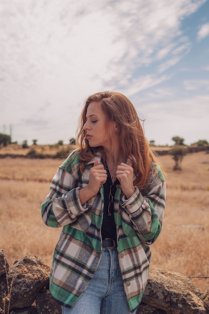 Una bella ragazza posa con un campo sullo sfondo