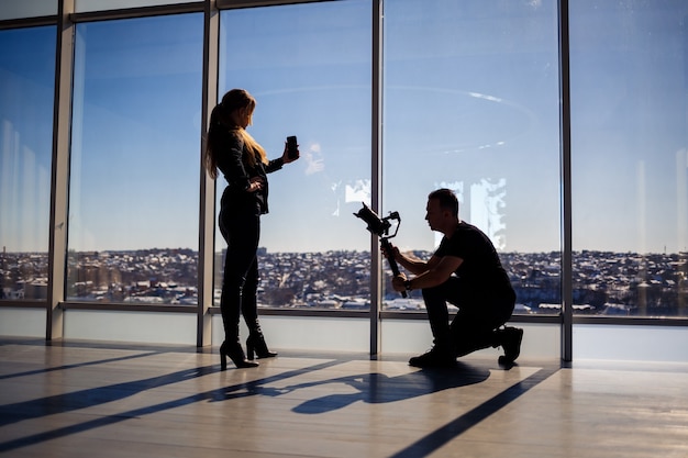 Una bella ragazza si fa un selfie con il telefono sullo sfondo di finestre panoramiche in un grattacielo