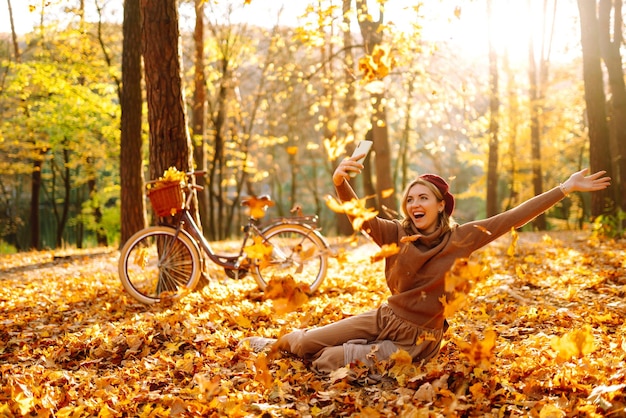 Una bella ragazza si fa un selfie nel parco d'autunno