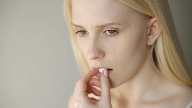 Una bella ragazza si mette una pillola sulla lingua e la beve con il primo piano dell'acqua.